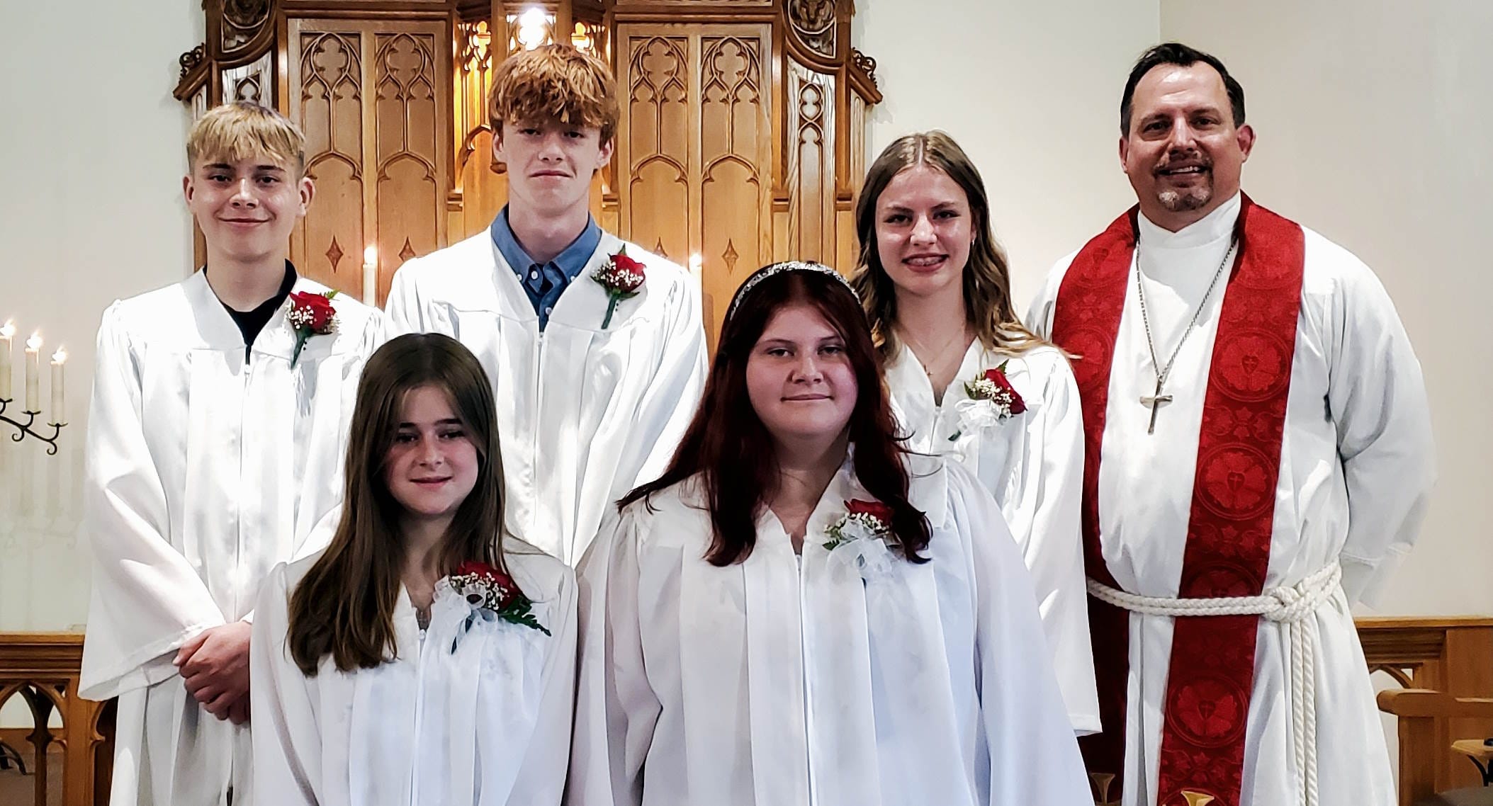 2024-10-17-catechism-class-confirmation Group of young people in white gowns and a male Lutheran pastor posing for a Confirmation picture.